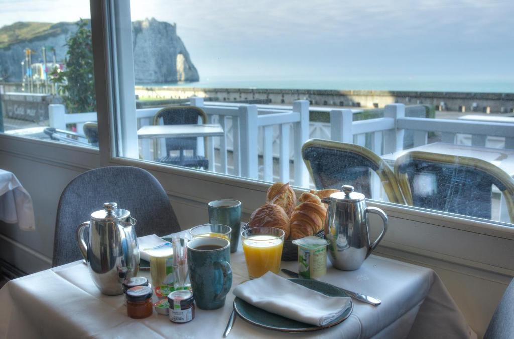 A breakfast table with a view of the sea and a cliff.