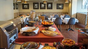 A buffet setup with various food items, a coffee machine, and seating arrangements in a restaurant. - Hotel Le Rayon Vert (Etretat)