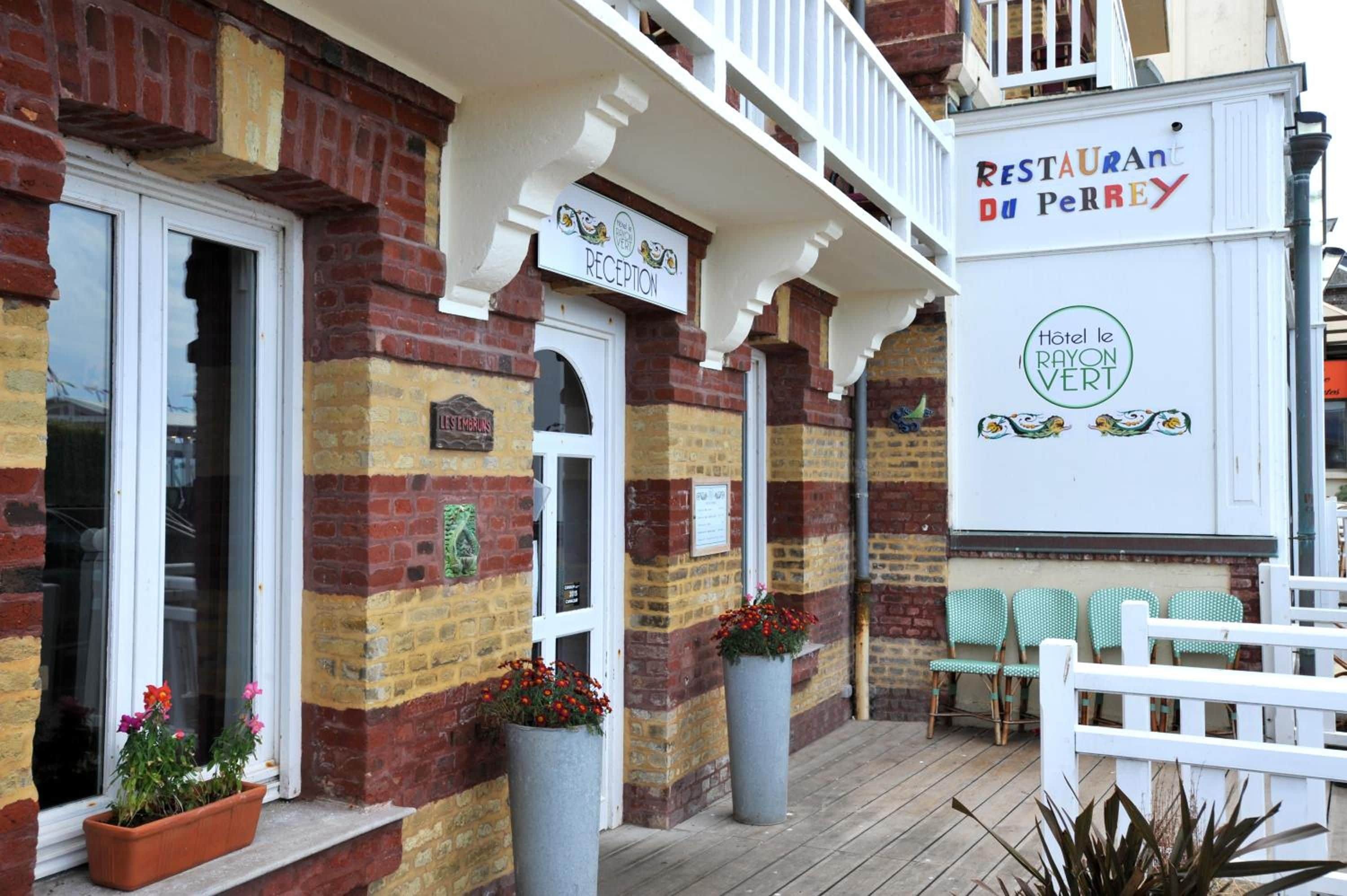 A building with a reception area, a sign for 'RESTAURANT du Perrey,' and a sign for 'Hotel le Rayon Vert.'