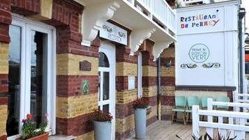 A building with a reception area, a sign for 'RESTAURANT du Perrey,' and a sign for 'Hotel le Rayon Vert.'