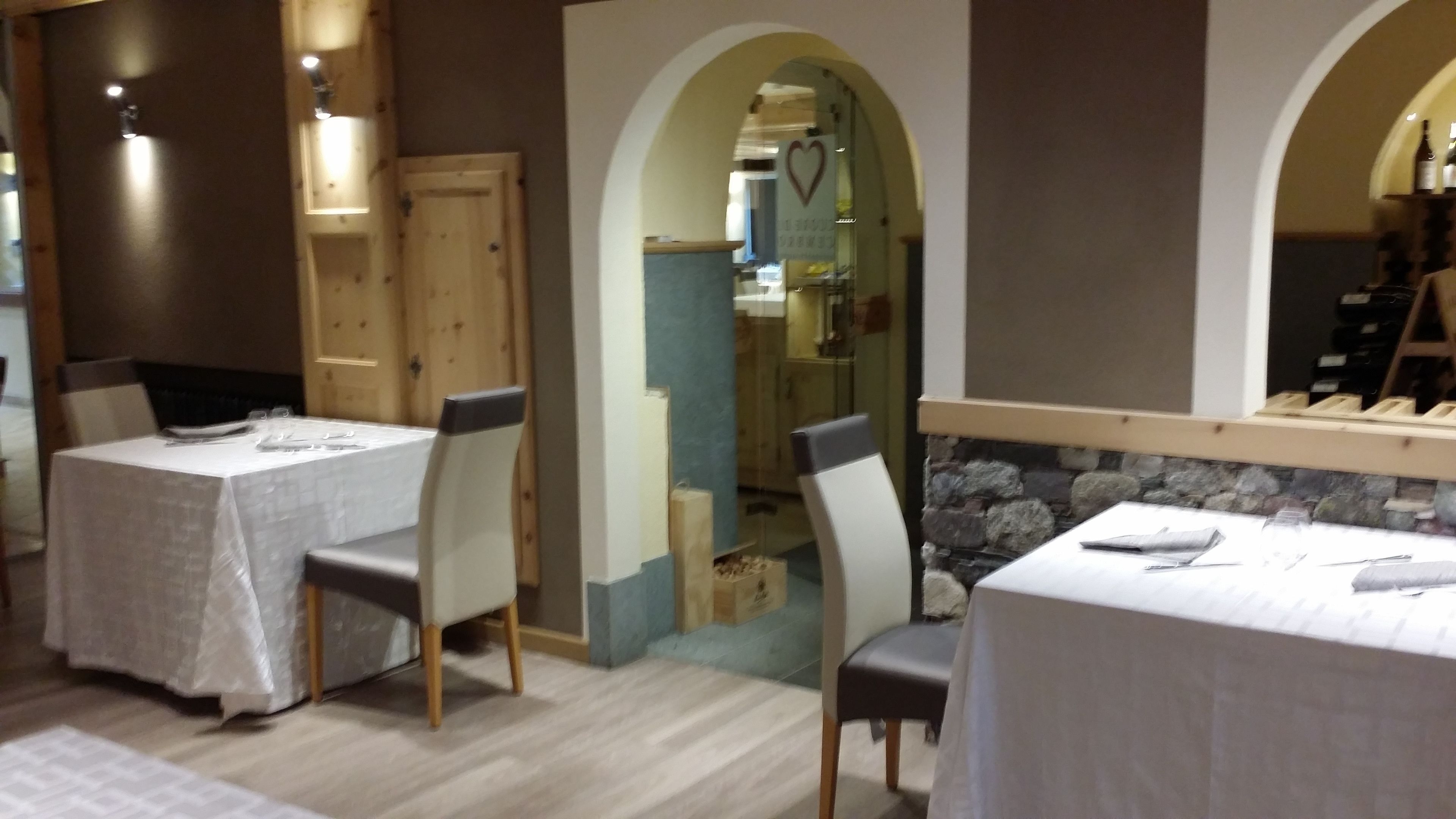 L’intérieur d’un restaurant est agrémenté de tables et de chaises en bois, de quelques éléments décoratifs en pierre et d’une porte vitrée qui donne sur l’espace cuisine.