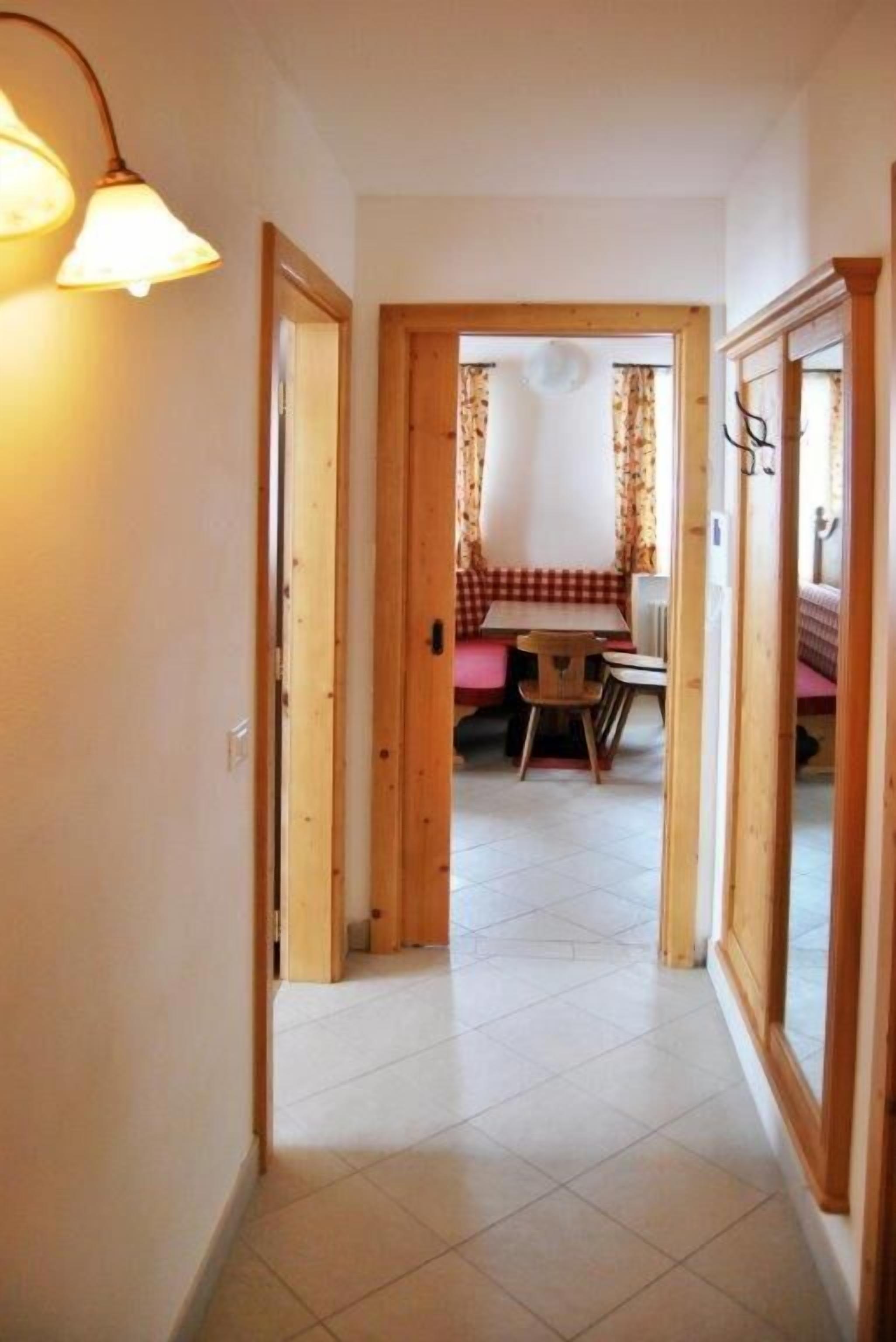 Un couloir mène à une salle à manger où se trouvent une table et des chaises en bois.