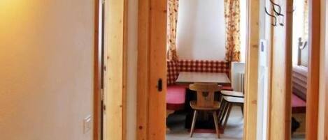 Un couloir mène à une salle à manger où se trouvent une table et des chaises en bois.