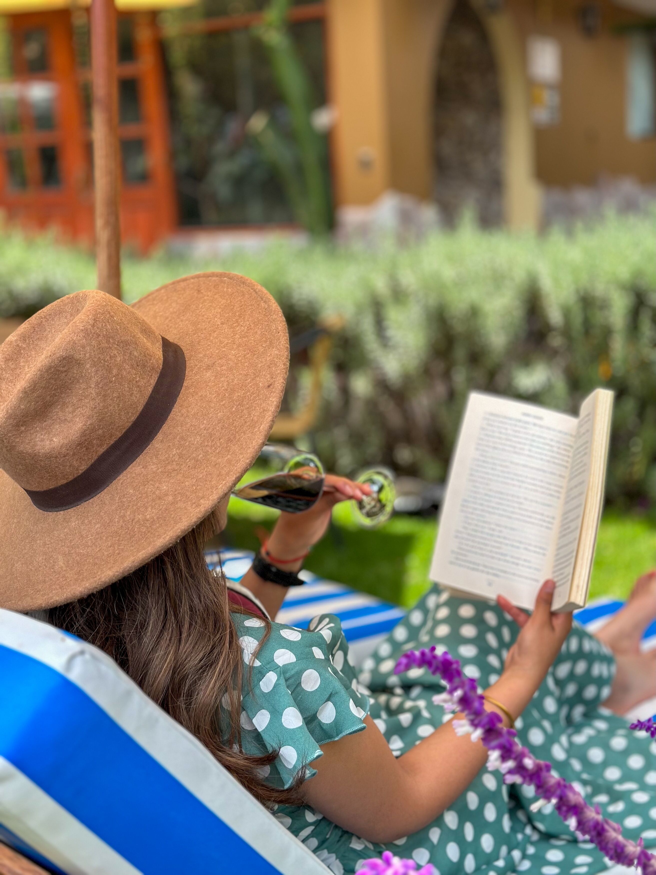 Une personne allongée sur une chaise longue, en train de lire un livre.