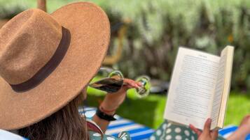 Une personne allongée sur une chaise longue, en train de lire un livre.