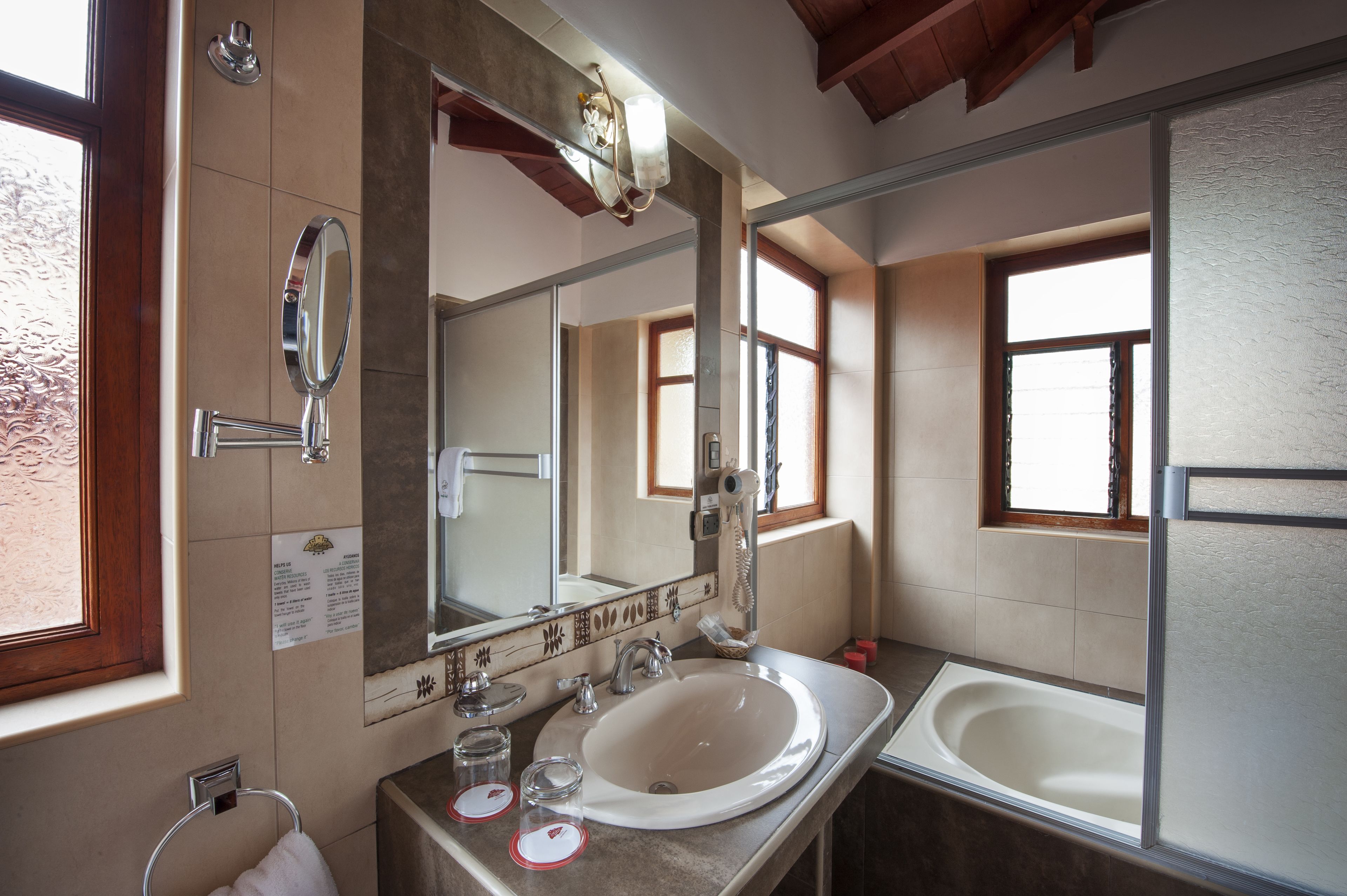 A bathroom with a large mirror, a sink, and a bathtub.