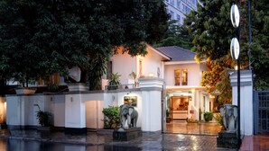A building with a white facade, a tiled roof, and a well-lit entrance. There are potted plants and a statue of an elephant near the entrance. - Skyline Boutique Hotel (Phnom Penh)
