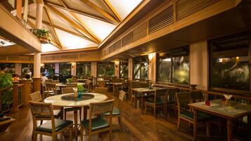 Un restaurante amplio con mobiliario de madera y ventanas grandes.