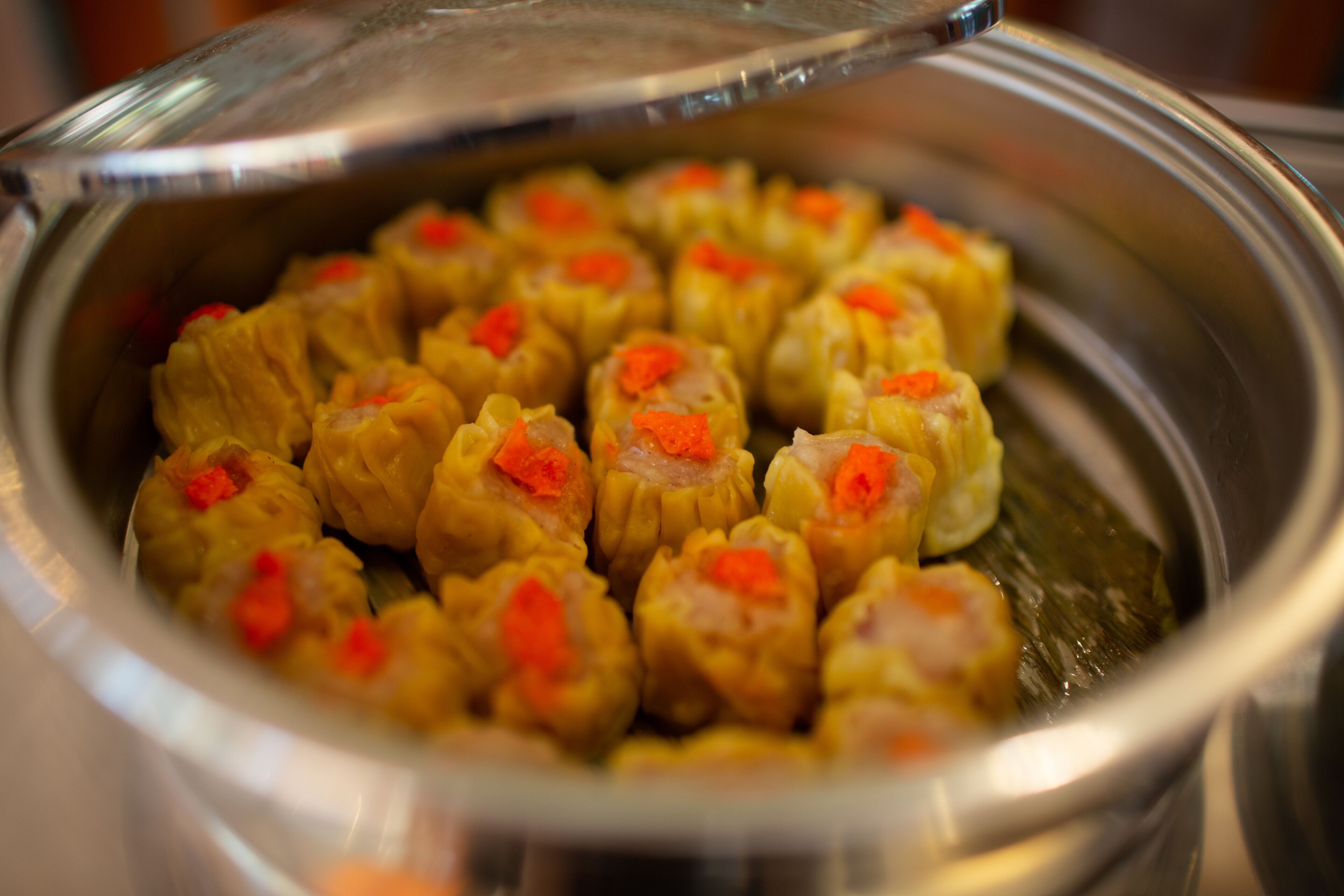 A stainless steel container filled with food items, likely dumplings, with a lid on top.