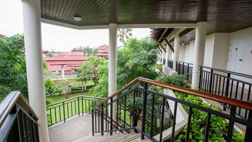 A covered outdoor staircase with a view of a garden and buildings in the background.