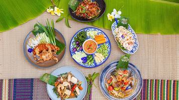A table with various dishes, including seafood and vegetables, arranged on a woven mat with a banana leaf.