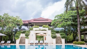 A swimming pool with lounge chairs and a covered seating area. - Maneechan Resort & Sport Club (Chanthaburi)