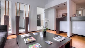 A modern living room with a dark wooden coffee table, magazines, and a potted orchid. - Saint James (Mons)