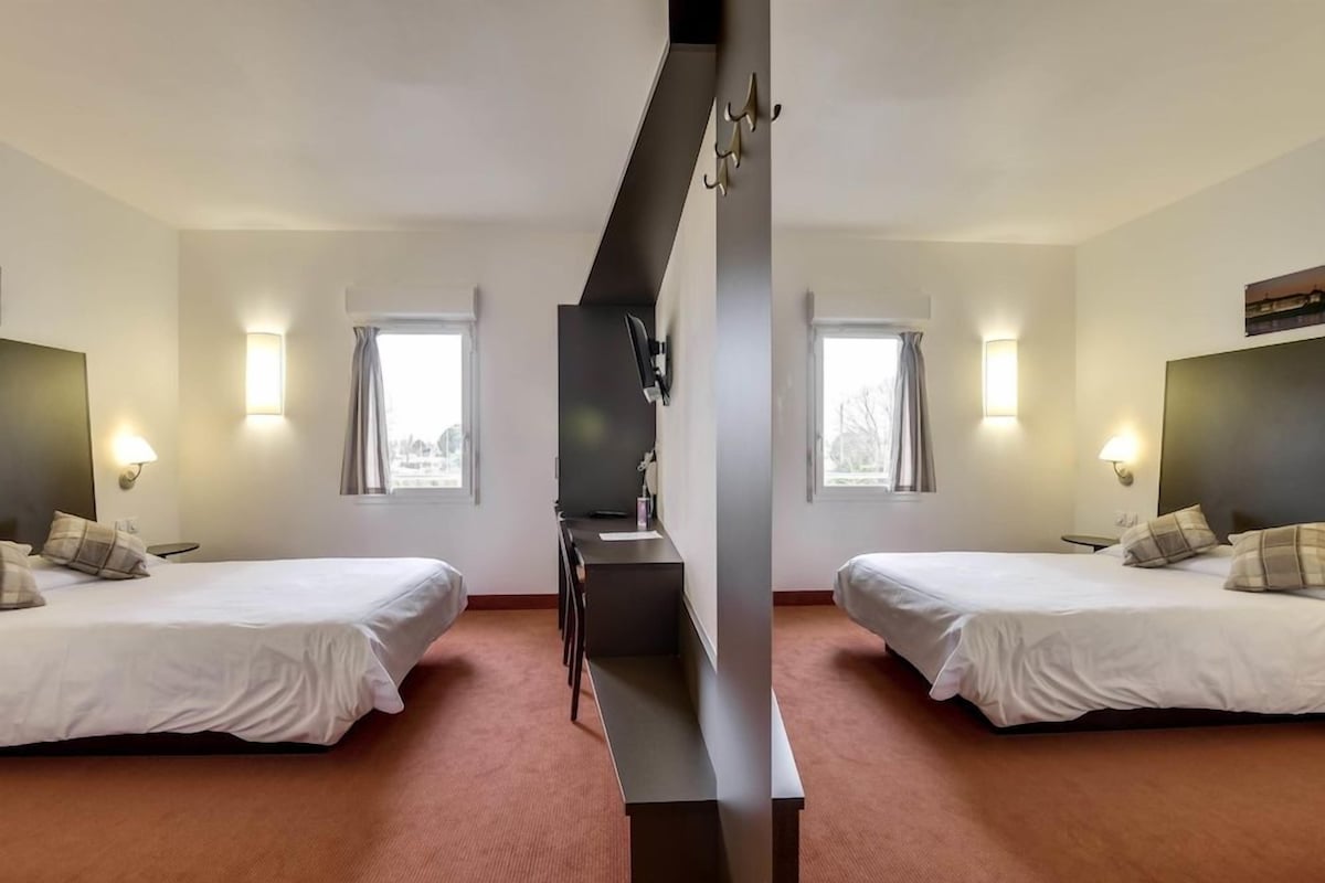 Een hotelkamer met twee bedden, een bureau en een televisie.