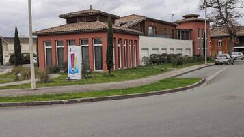 A building with a tiled roof, a signboard, and a road with parked cars.