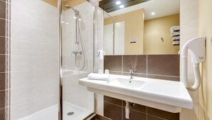Une salle de bain moderne avec une douche à parois de verre, un lavabo blanc et un sèche-cheveux.