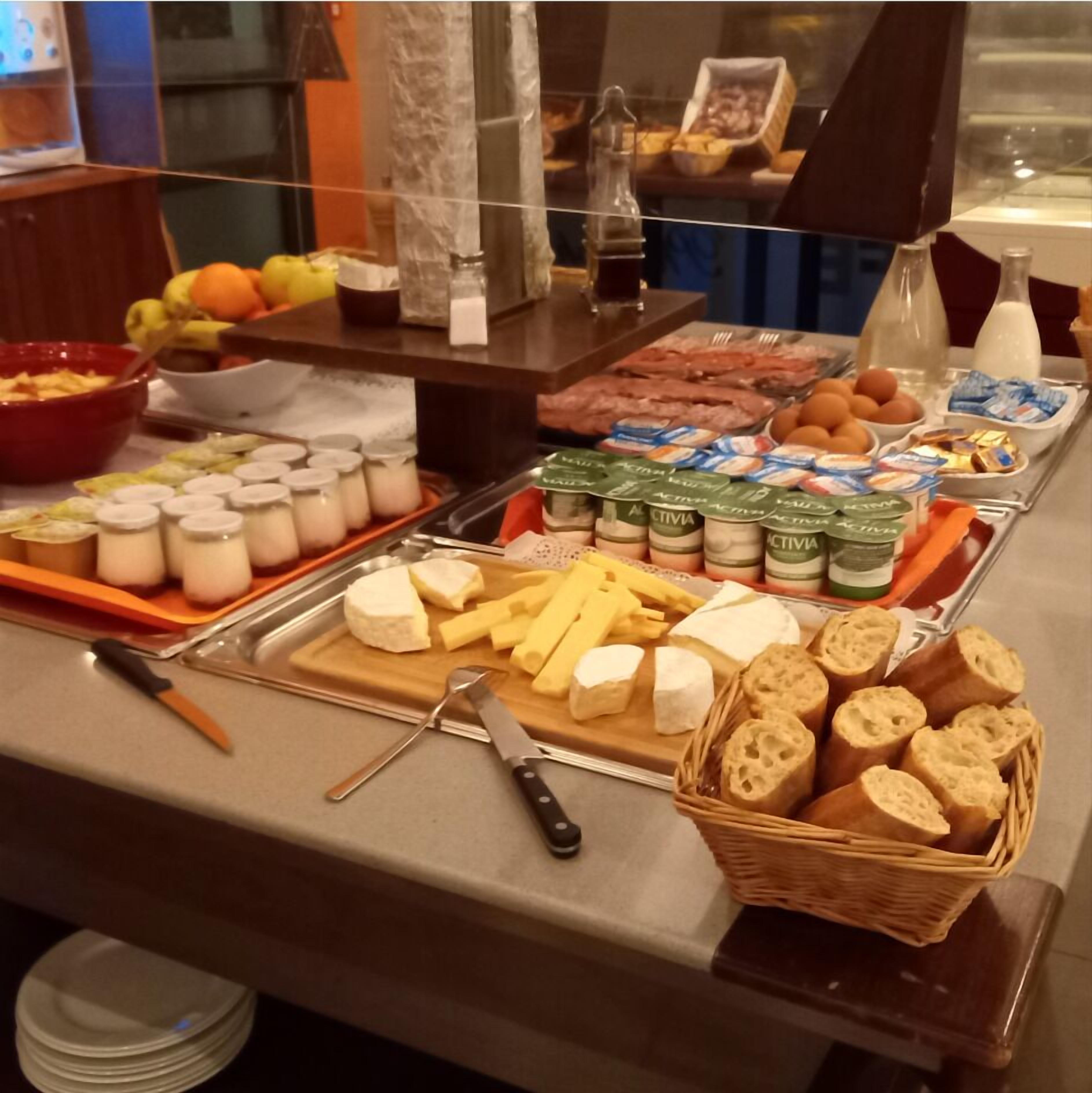Un buffet con formaggi, pane, frutta e latticini.