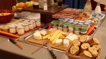 A buffet with cheese, bread, fruits, and dairy products.