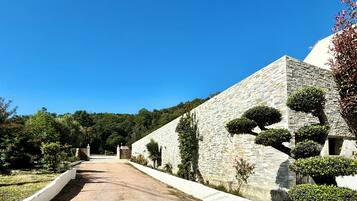 Un sendero conduce a un edificio de piedra con cúpula, rodeado de jardines cuidados y árboles.