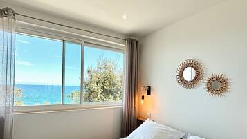 Un dormitorio con una cama grande, vista al mar y dos espejos colgados en la pared.