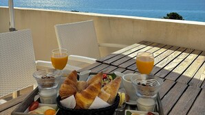 Bandeja de desayuno sobre una mesa de madera con vista al océano.
