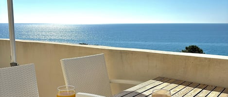 A breakfast tray on a wooden table with a view of the ocean.