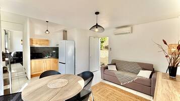 A modern living space with a dining area, kitchen, and a sofa.