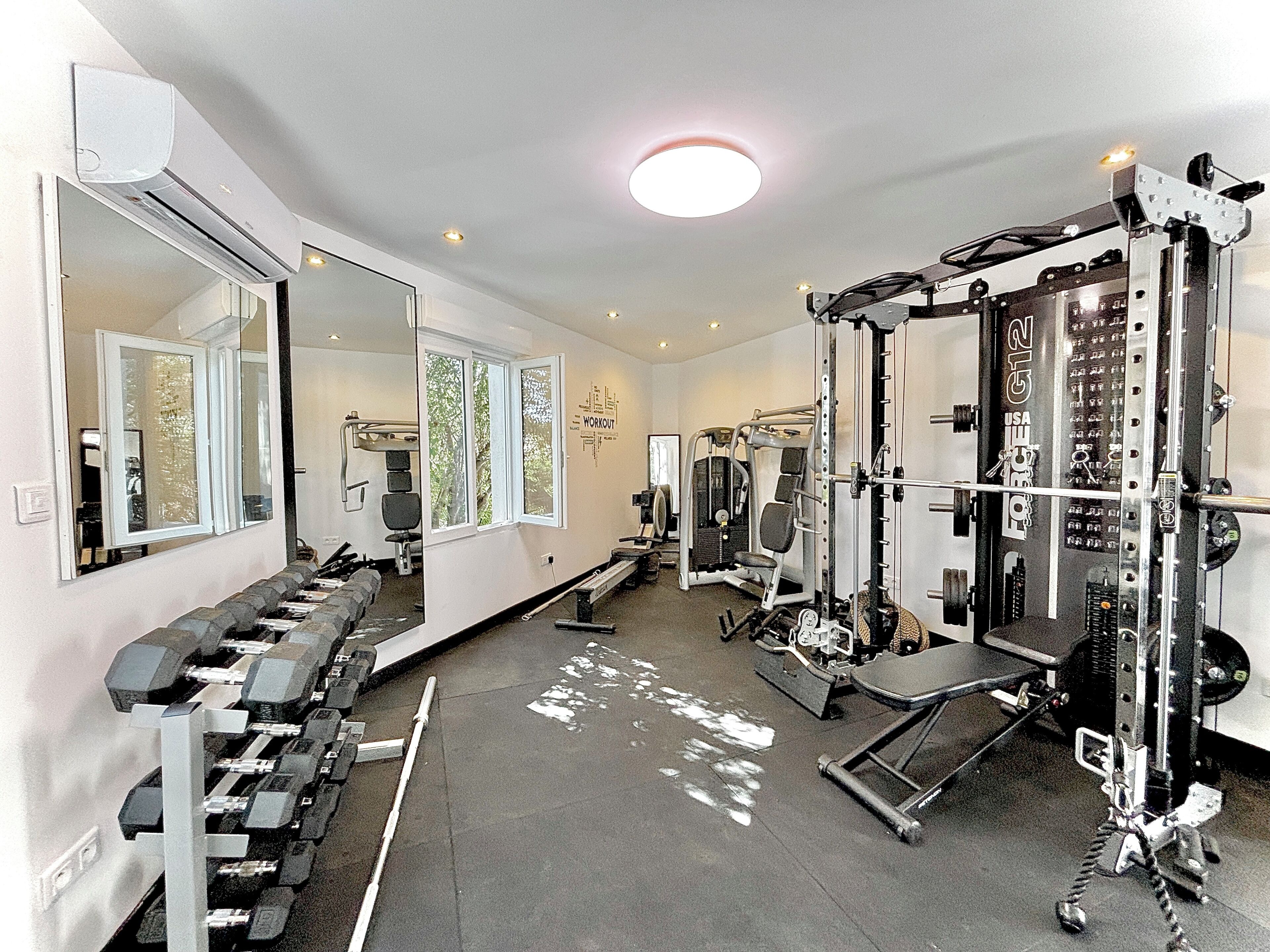 A gym with weight machines, a bench, and a mirror.
