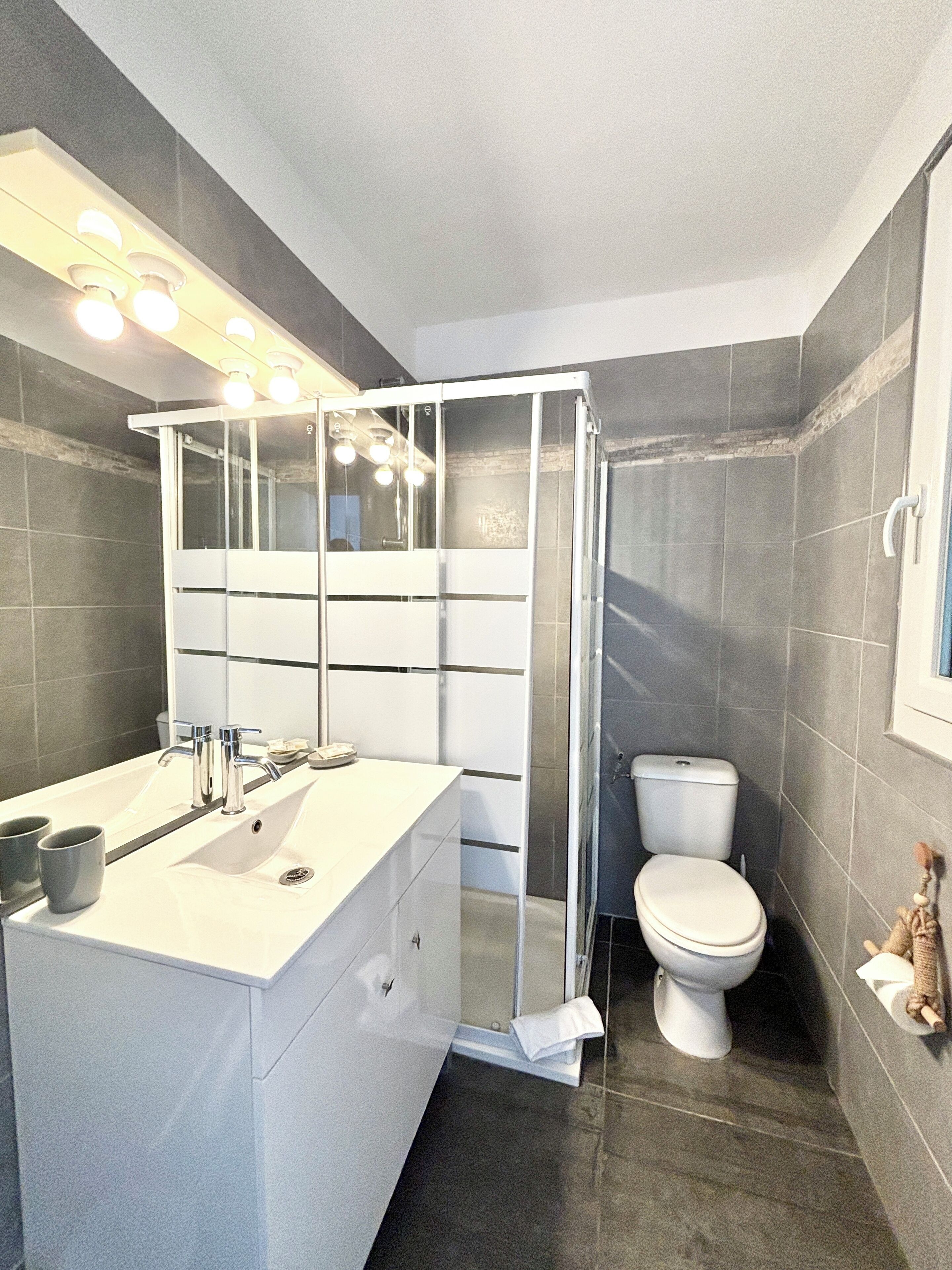 A modern bathroom with a white vanity, a glass shower enclosure, and a toilet.