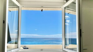 Una ventana abierta con vista al océano y un cielo despejado.