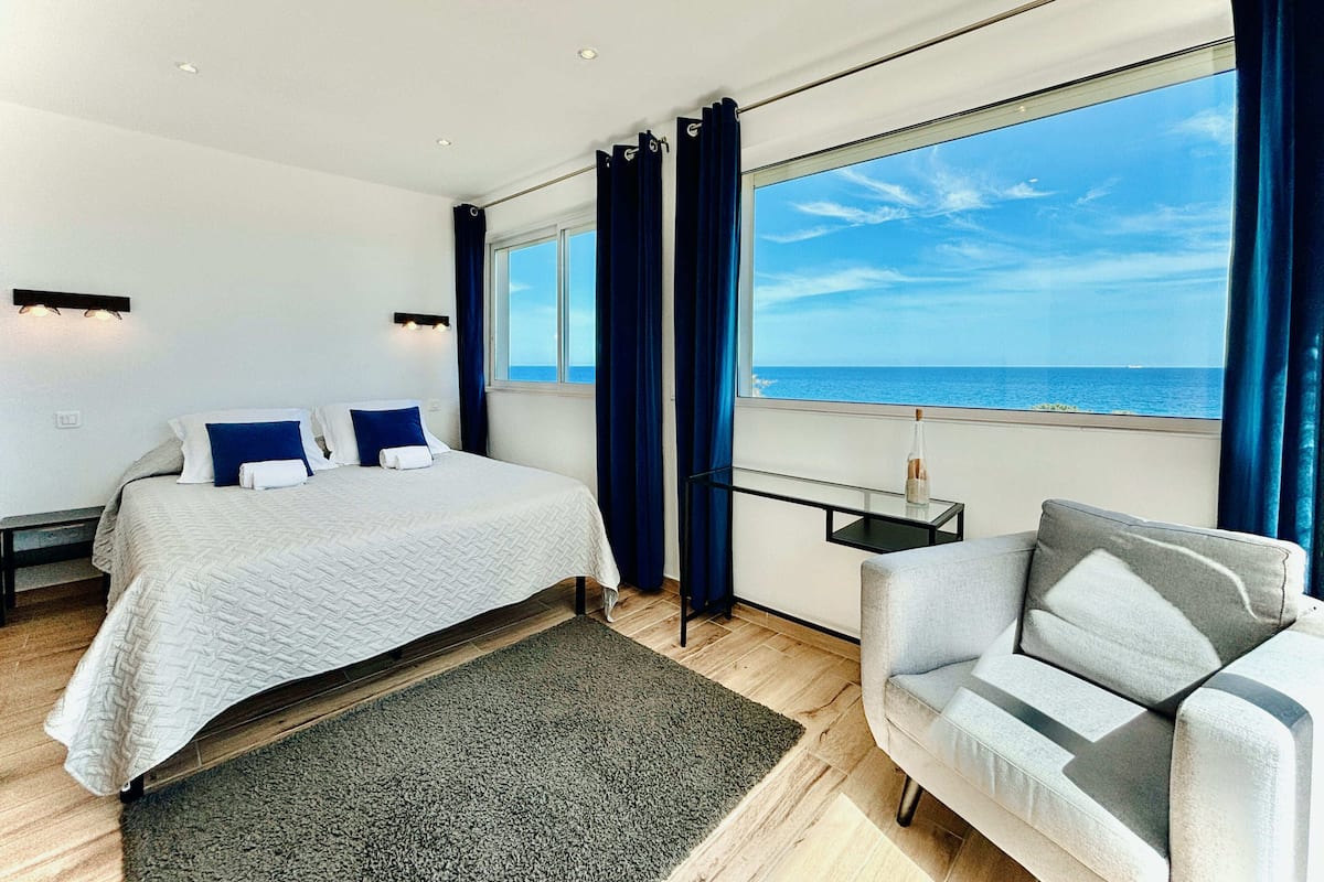 Ein modernes Hotelzimmer mit einem großen Bett, einer Sitzecke und Meerblick.