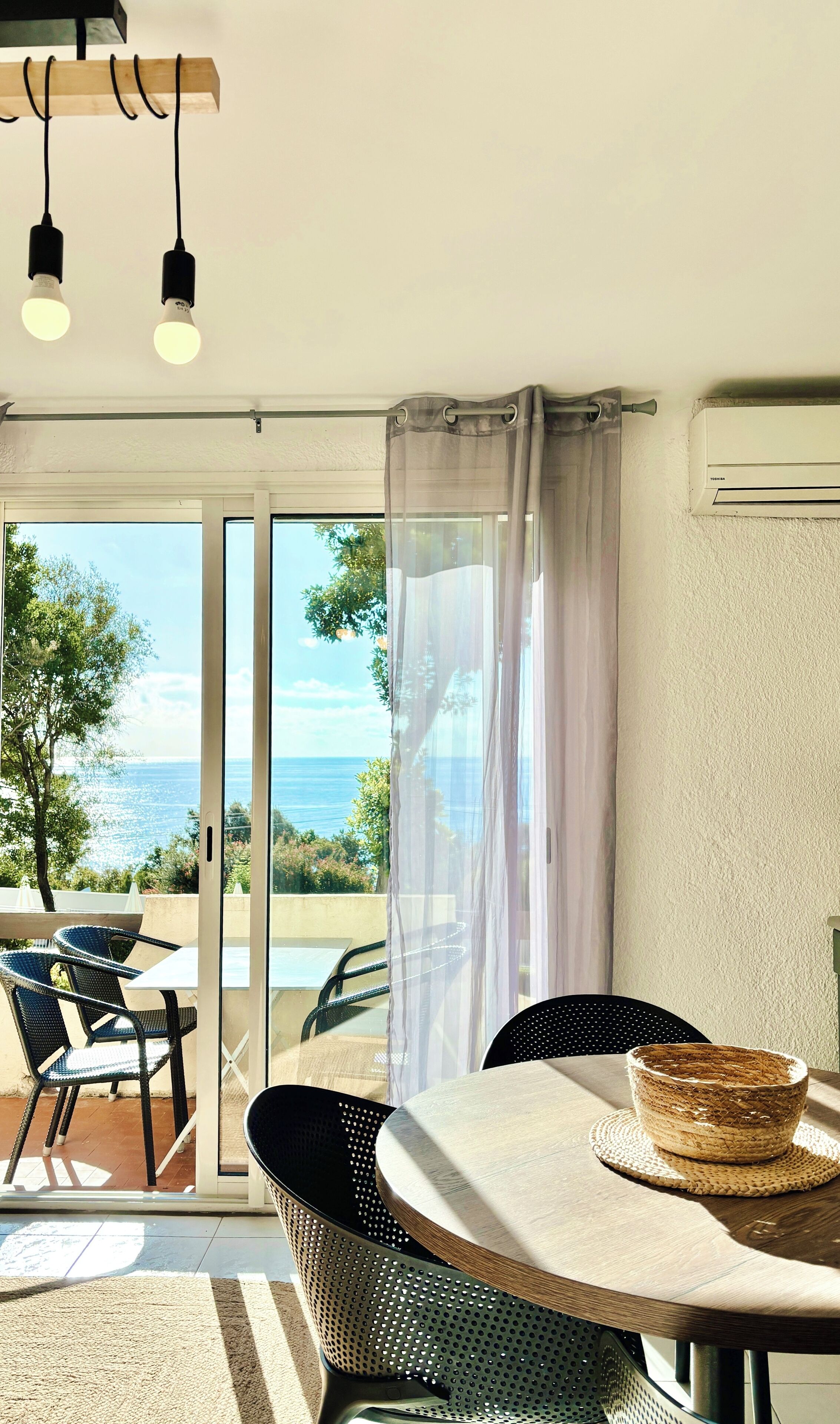 A dining area with a table, chairs, and a view of the sea.