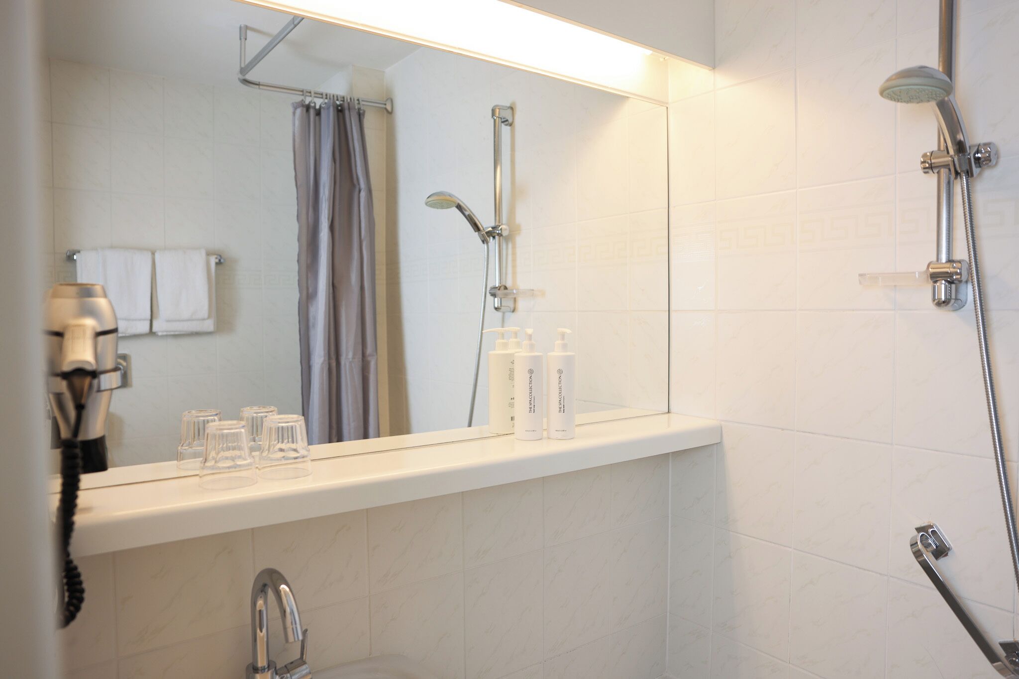 A bathroom with a mirror, a shower, and a sink.