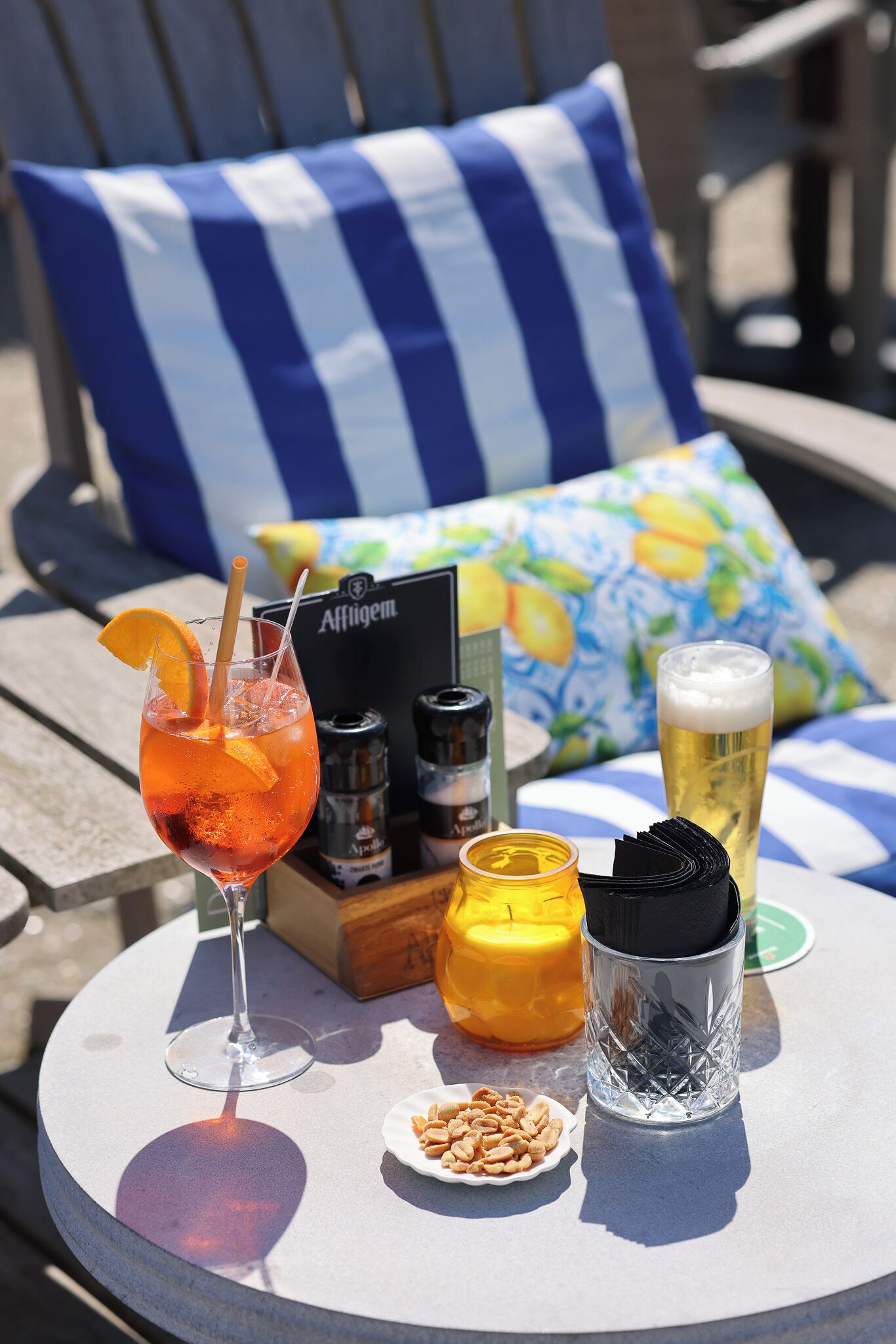 A table with a drink, a candle, a box, and a bottle.