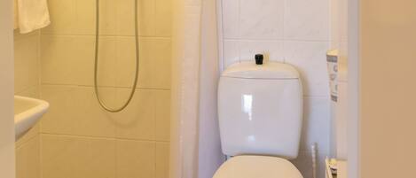 A small, clean bathroom with a shower, toilet, and sink.