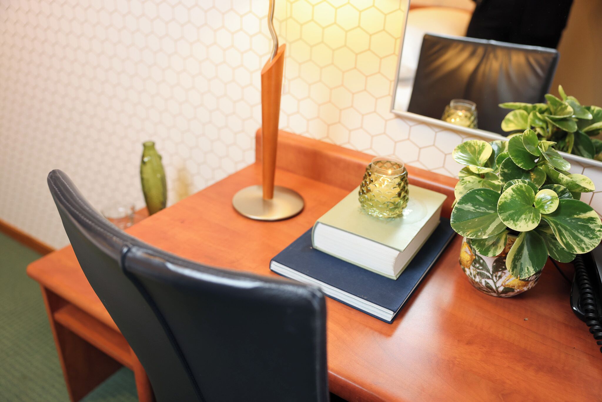 A wooden table with a book, a glass candle, and a potted plant.