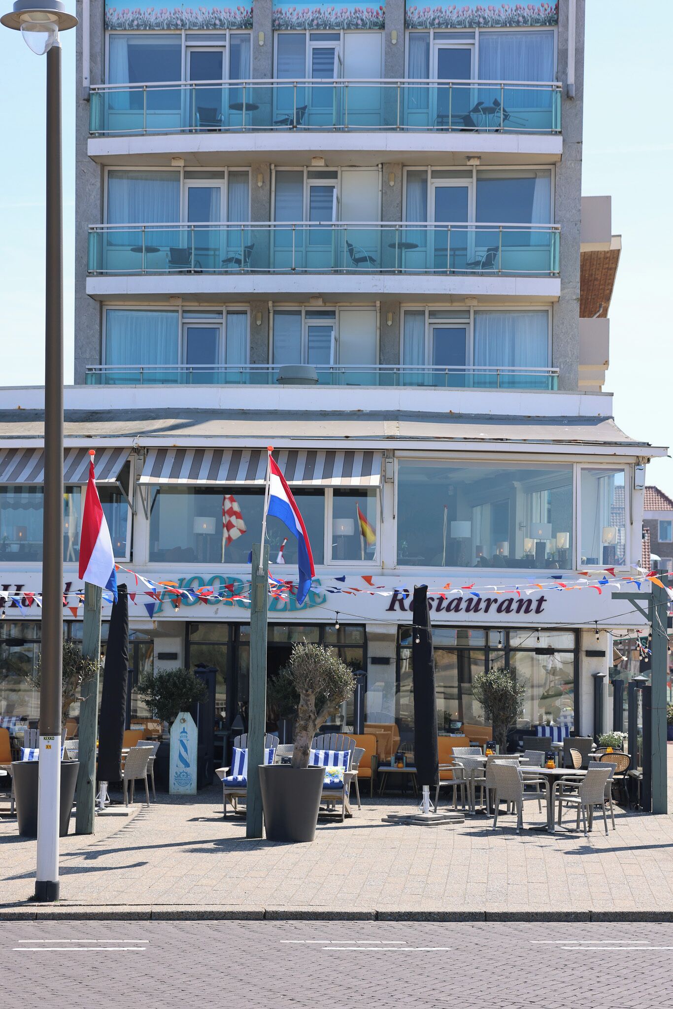 Een restaurant met terras, een bord en vlaggen.