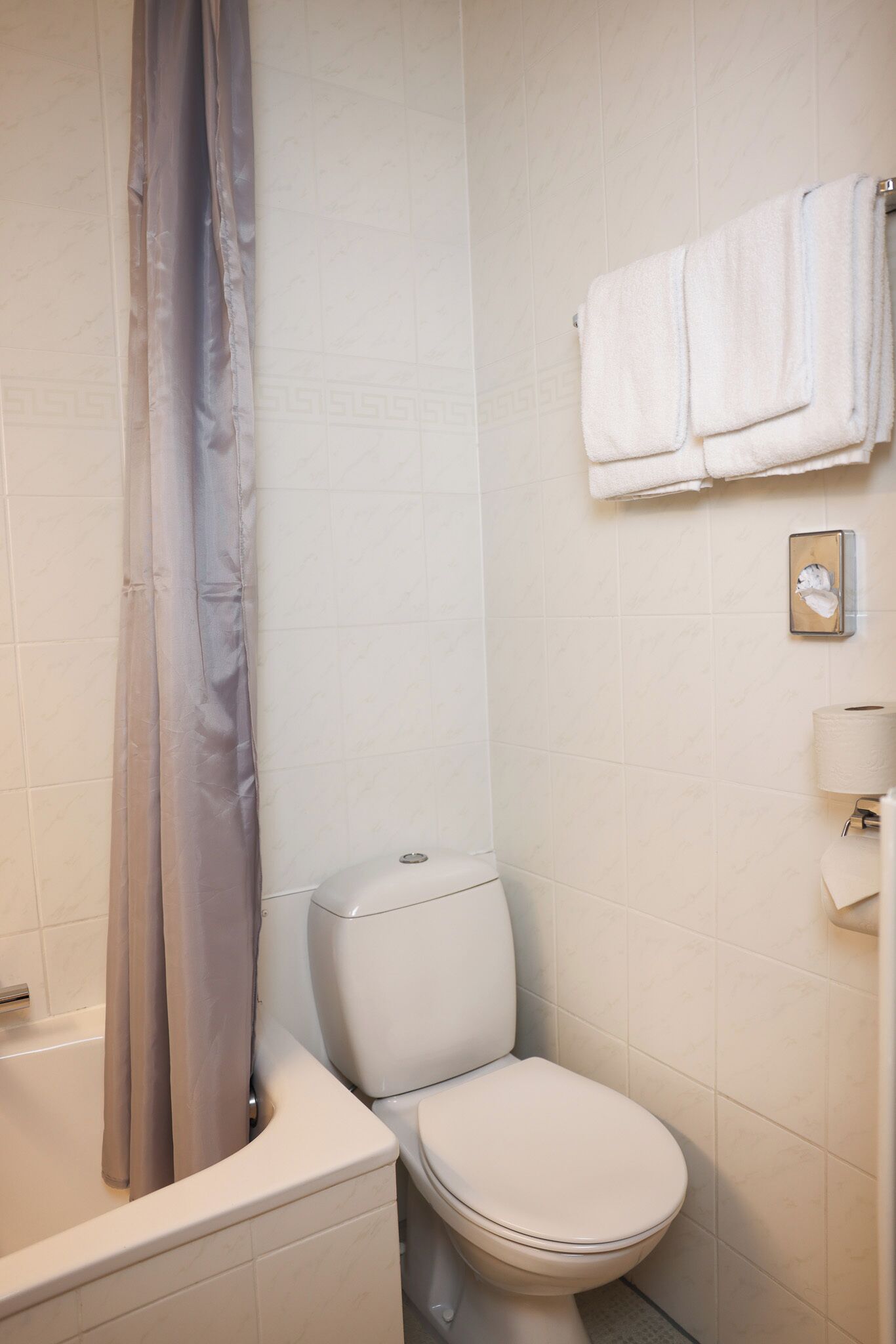 A bathroom with a bathtub, toilet, and a towel rack with towels.