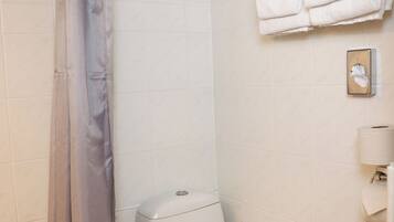 A bathroom with a bathtub, toilet, and a towel rack with towels.