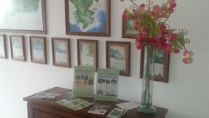 Un comptoir d’accueil orné de cartes encadrées et de panneaux d’information, un vase rempli de fleurs et un tableau d’affichage où sont accrochées des brochures.