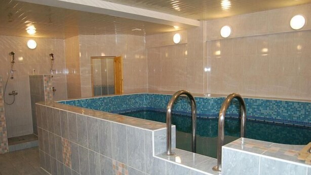 Une salle de bain moderne avec une piscine rectangulaire, des murs carrelés et un espace douche.