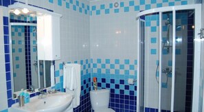 A bathroom with a white sink, a mirror, a toilet, and a shower area. - Victoria Palace Hotel (Atyrau)