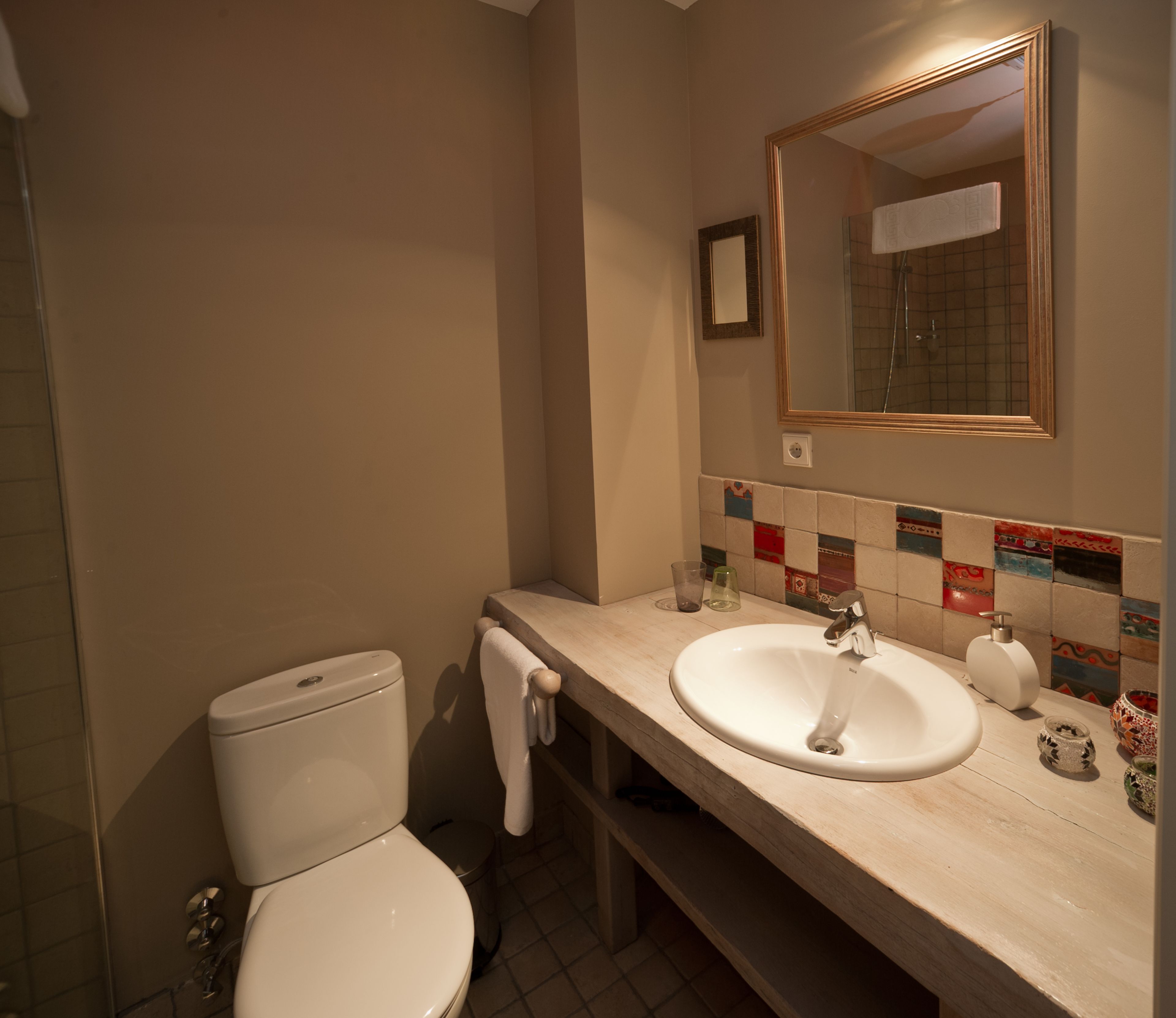 A bathroom with a toilet, sink, and mirror.