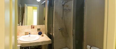 A bathroom with a glass-enclosed shower, a sink, and a toilet.