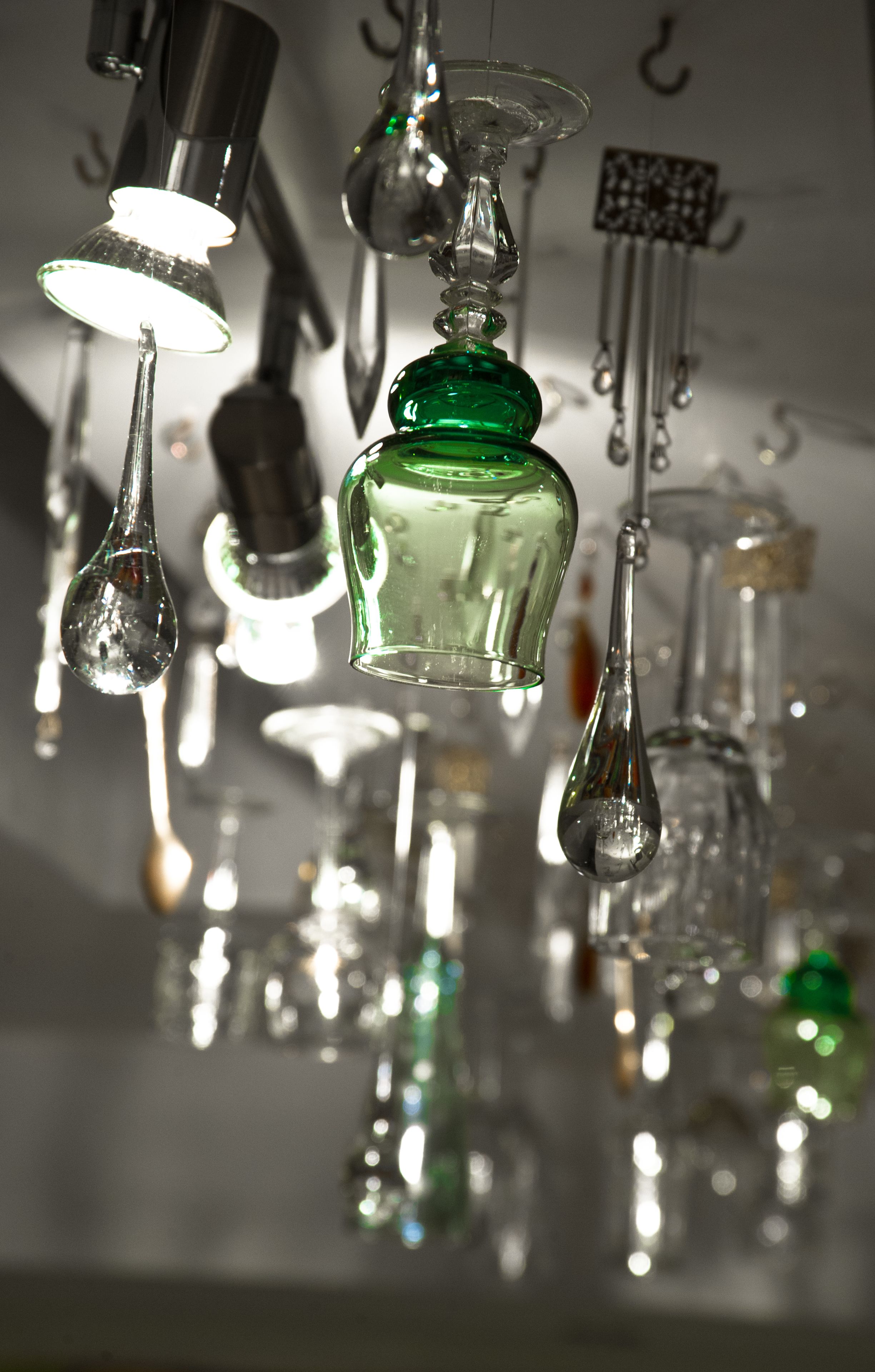 A collection of hanging glassware, including bottles and teapots, suspended from the ceiling.