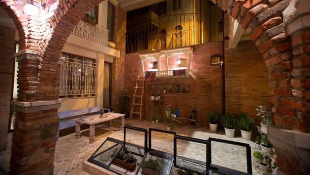 A courtyard with brick walls, a wooden bench, and potted plants. - No12 Boutique Hotel (Tbilisi)