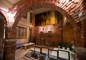 A courtyard with brick walls, a wooden bench, and potted plants. - No12 Boutique Hotel (Tbilisi)