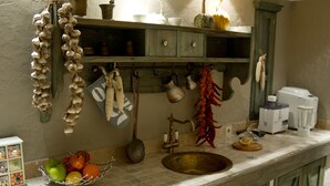 A kitchen with wooden cabinets, a sink, and various kitchen utensils hanging on the wall. - No12 Boutique Hotel (Tbilisi)