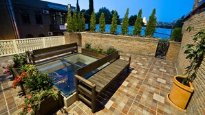 A rooftop terrace with a glass-enclosed hot tub, wooden benches, and potted plants. - No12 Boutique Hotel (Tbilisi)