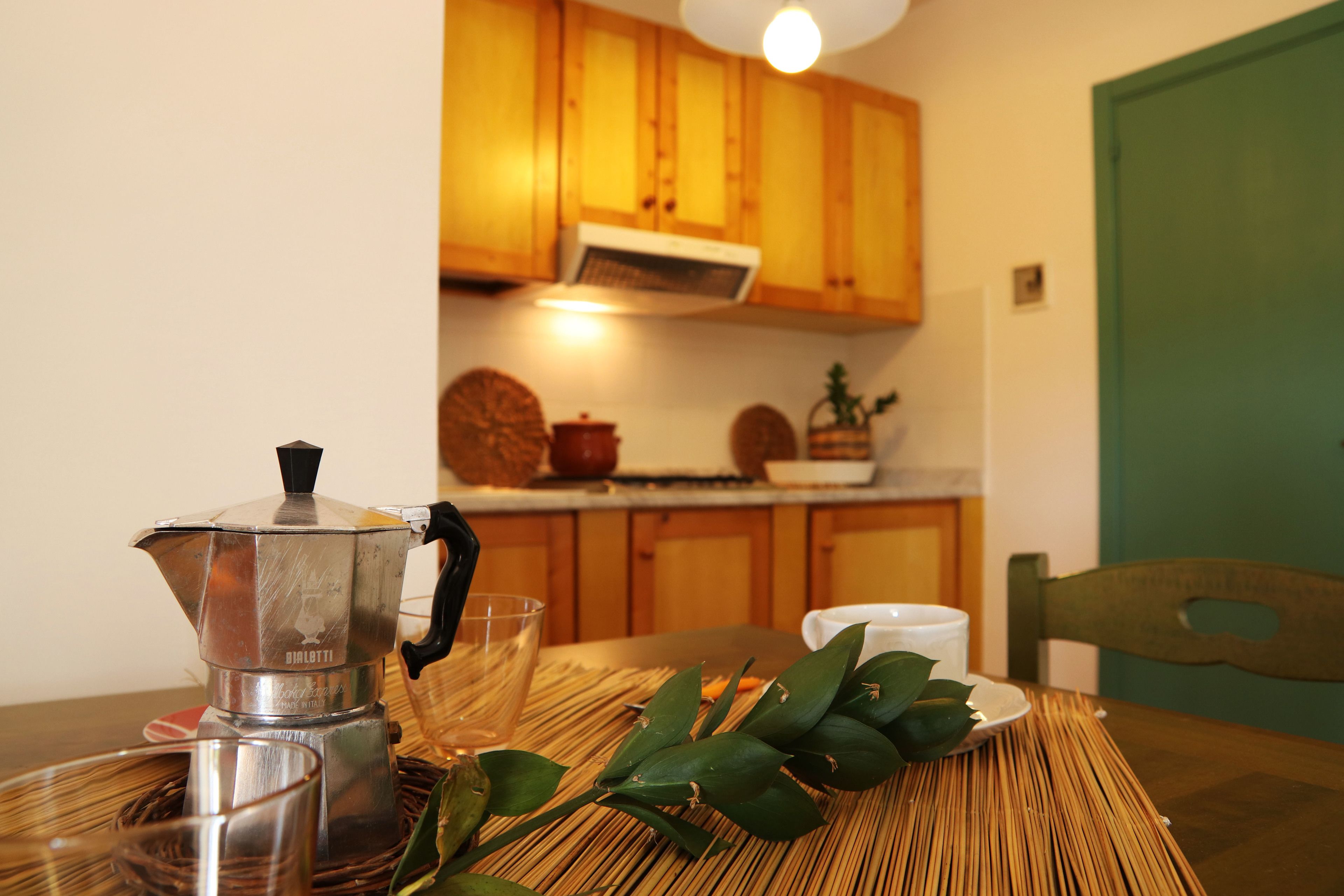 A kitchen with wooden cabinets, a coffee maker, a glass, and a plate with leaves.